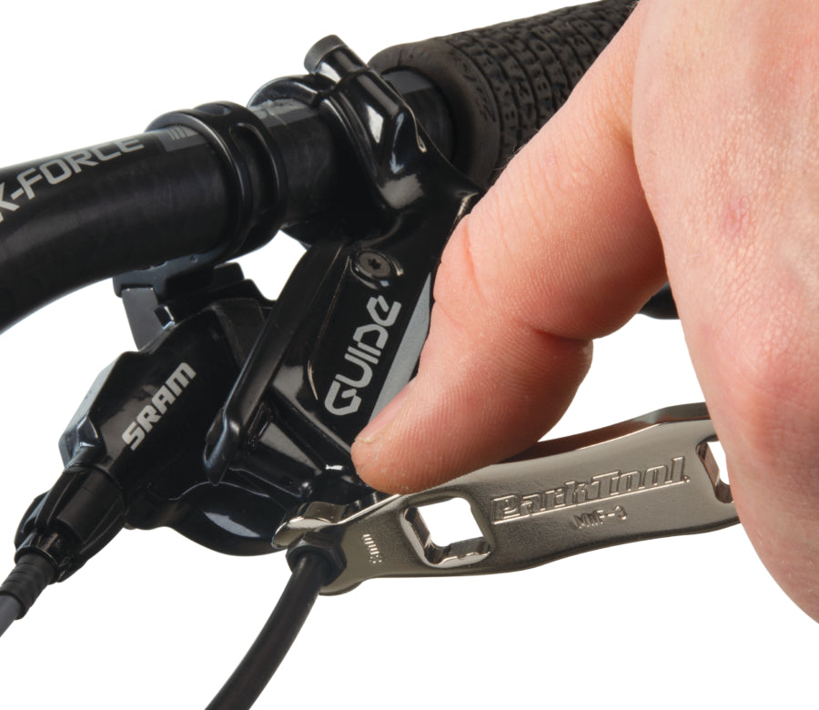 Park Tool MWF-3 draait een remleidingkoppeling op een remhendel aan